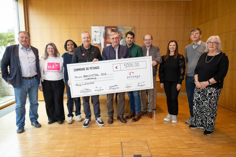 Dix personnes posent derrière un chèque de 5 000 € de la Commune de Pétange en faveur d’ELA Luxembourg