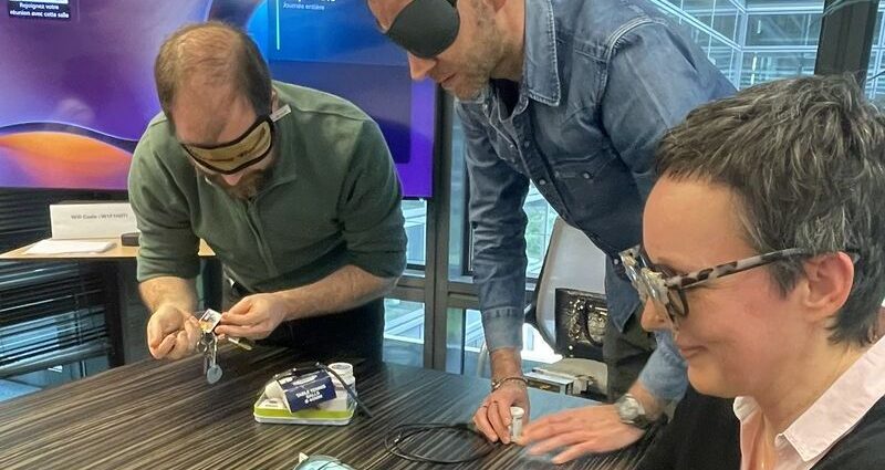 Des collaborateurs, les yeux bandés, assemblent un puzzle lors d'un atelier de mise en situation